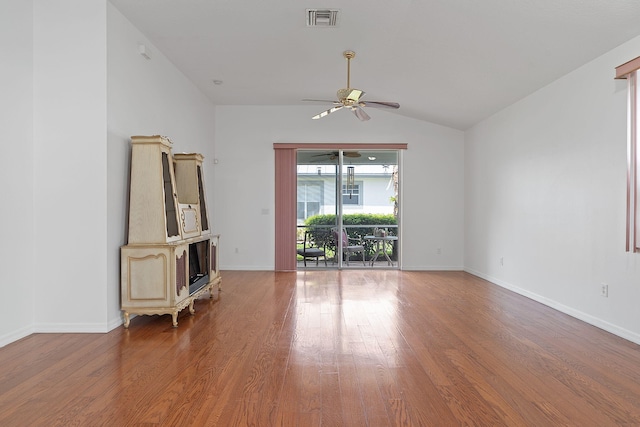 spare room featuring a wood stove, ceiling fan, hardwood / wood-style floors, and lofted ceiling