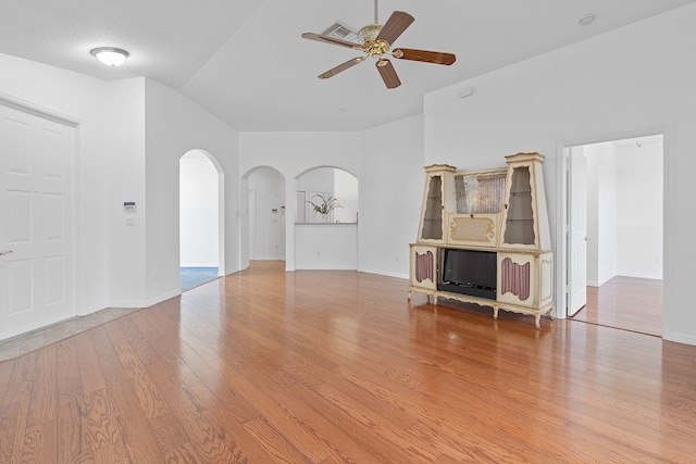 unfurnished living room with lofted ceiling, ceiling fan, and light wood-type flooring