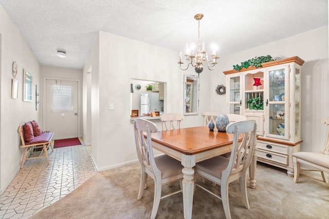 carpeted dining area featuring a textured ceiling and a notable chandelier