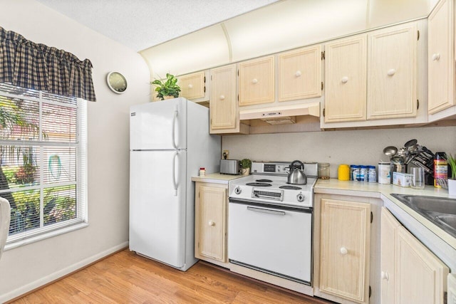 kitchen featuring white appliances, light brown cabinets, light hardwood / wood-style floors, and a textured ceiling