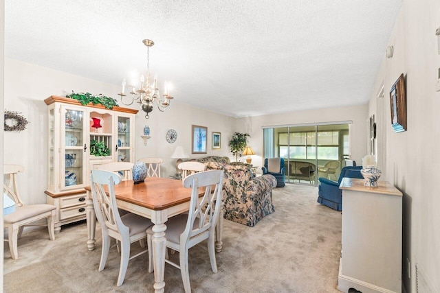 dining area featuring a textured ceiling, an inviting chandelier, and light carpet