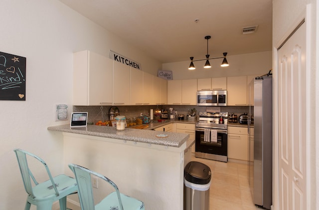 kitchen with pendant lighting, stainless steel appliances, kitchen peninsula, and decorative backsplash