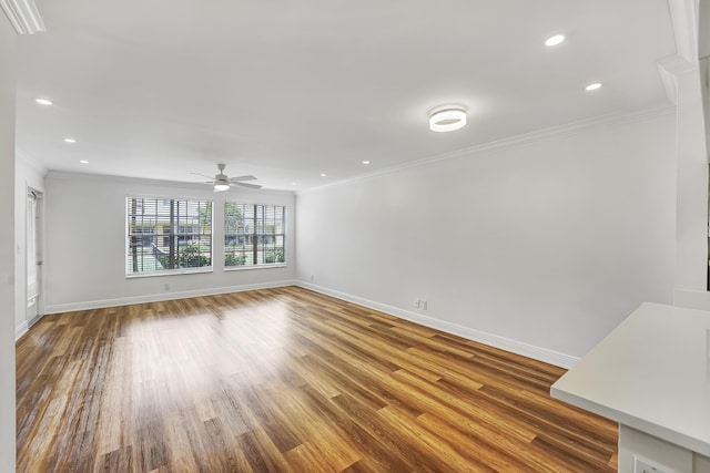 unfurnished living room with ornamental molding, ceiling fan, wood finished floors, and baseboards