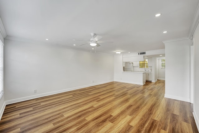 unfurnished living room with baseboards, ornamental molding, ceiling fan, recessed lighting, and light wood finished floors