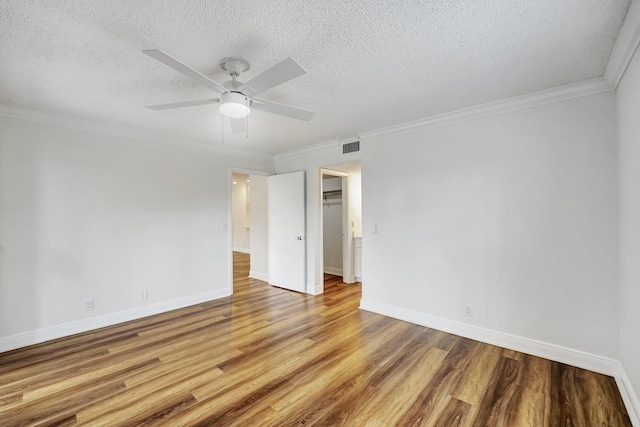 empty room featuring ceiling fan, a textured ceiling, crown molding, and wood-type flooring