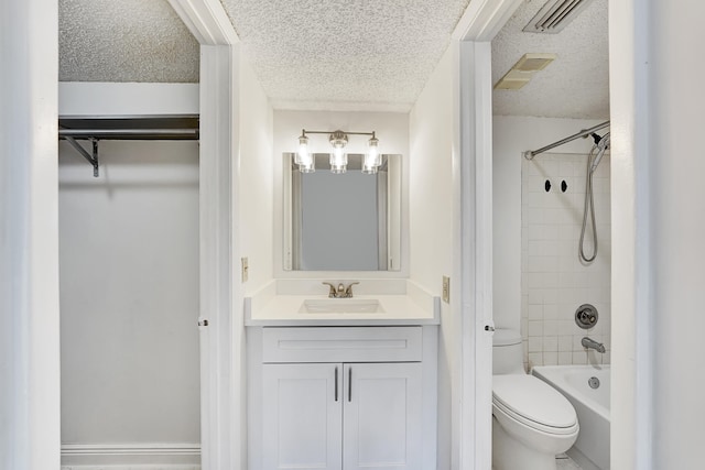 full bathroom with tiled shower / bath, vanity, toilet, and a textured ceiling