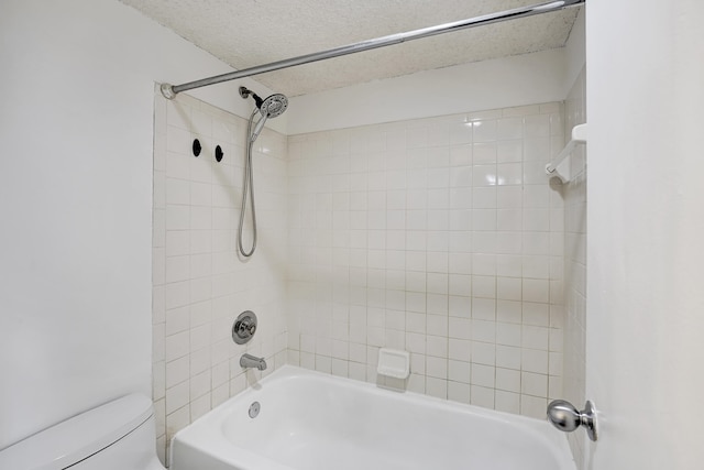 bathroom with a textured ceiling, tiled shower / bath combo, and toilet