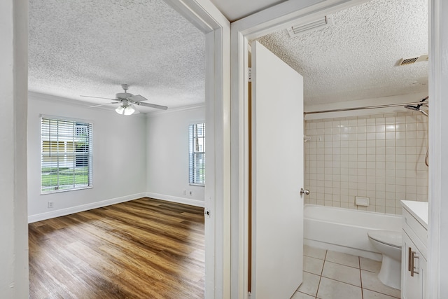 full bathroom featuring ceiling fan, tiled shower / bath, vanity, hardwood / wood-style flooring, and toilet