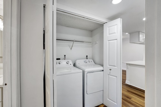 clothes washing area featuring recessed lighting, laundry area, washing machine and clothes dryer, and wood finished floors