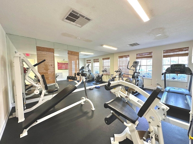 exercise room featuring visible vents, baseboards, and a textured ceiling