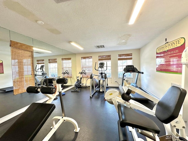 gym with visible vents, a textured ceiling, and baseboards