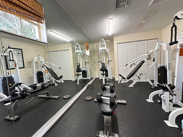 exercise room featuring visible vents, baseboards, and a textured ceiling