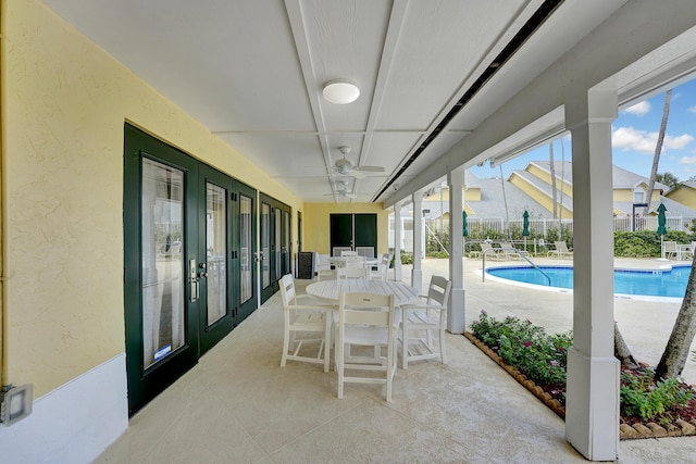 view of patio with a community pool, ceiling fan, fence, and outdoor dining space