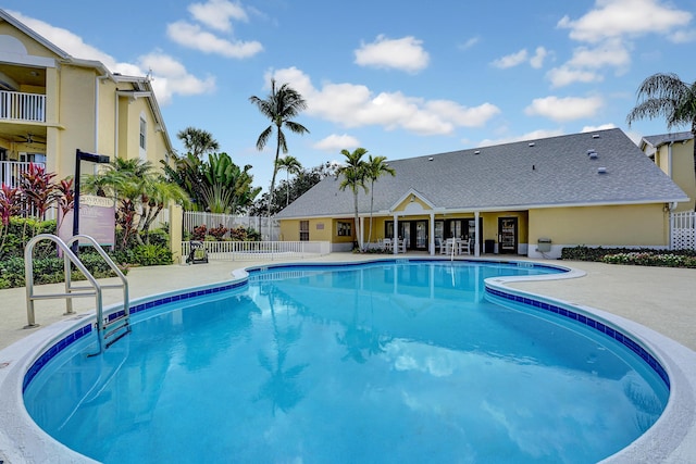 community pool with a patio area and fence