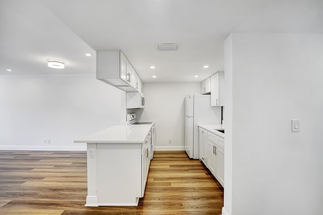 kitchen with light wood-type flooring, white appliances, ornamental molding, and white cabinets