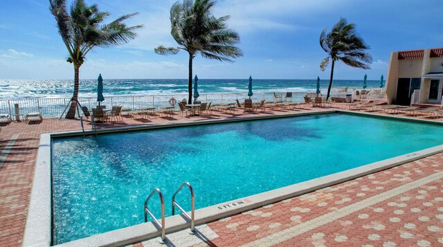 view of swimming pool with a water view and a patio