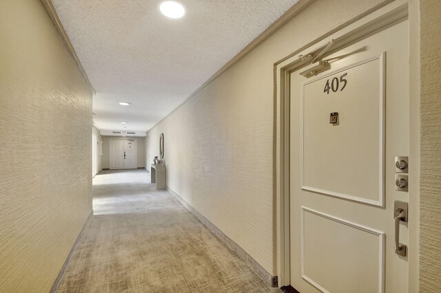 hallway featuring light carpet, a textured ceiling, and ornamental molding