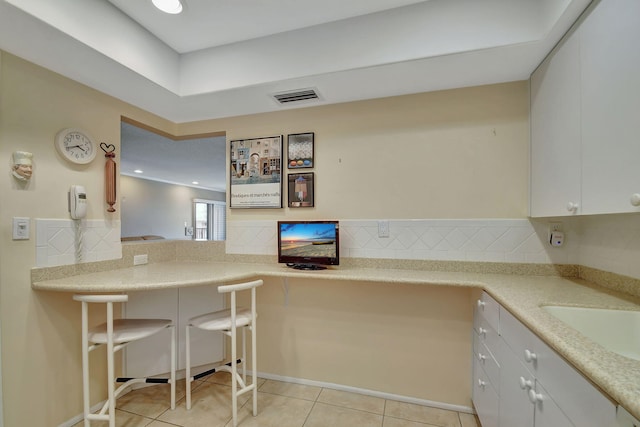 kitchen with backsplash, white cabinets, sink, and light tile patterned floors