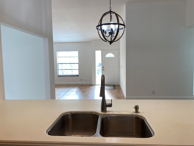 kitchen featuring pendant lighting, hardwood / wood-style flooring, a notable chandelier, and sink