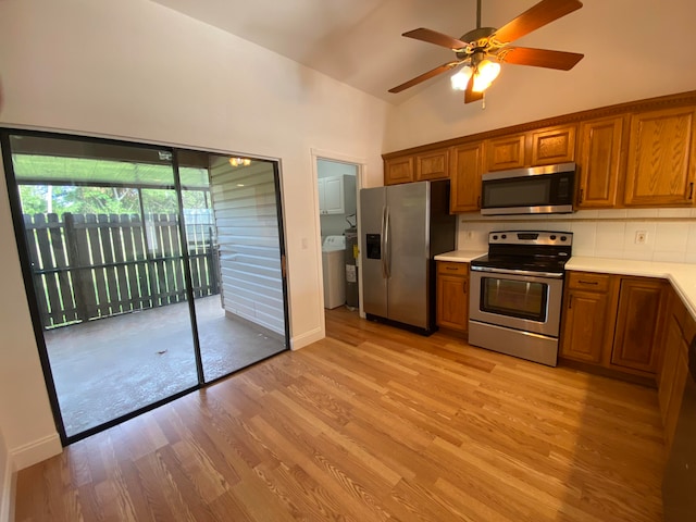 kitchen with light wood-type flooring, backsplash, stainless steel appliances, ceiling fan, and washer / dryer