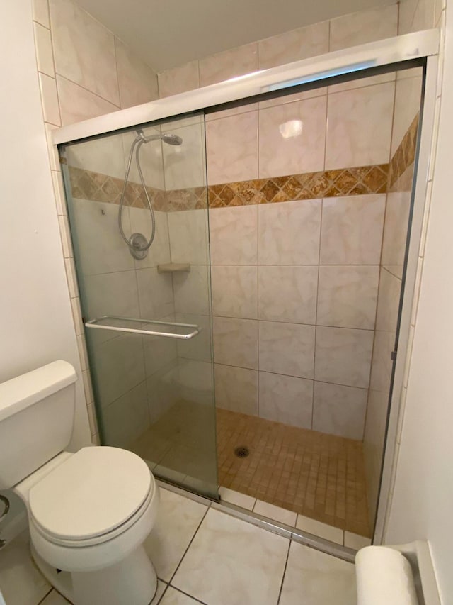 bathroom with toilet, a shower with shower door, and tile patterned floors