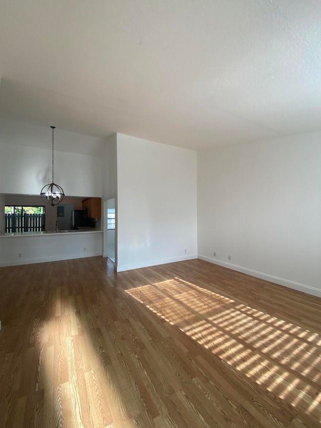 unfurnished living room with hardwood / wood-style floors, a notable chandelier, and a healthy amount of sunlight