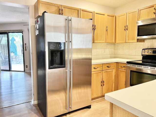 kitchen featuring decorative backsplash, light hardwood / wood-style floors, light brown cabinetry, and appliances with stainless steel finishes