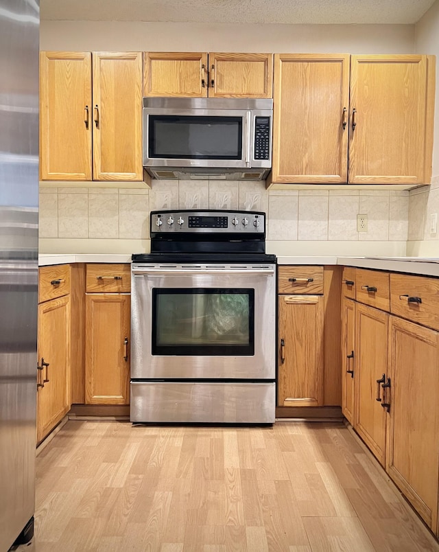 kitchen featuring decorative backsplash, stainless steel appliances, and light wood-type flooring