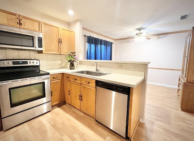 kitchen with light hardwood / wood-style floors, kitchen peninsula, appliances with stainless steel finishes, a textured ceiling, and sink