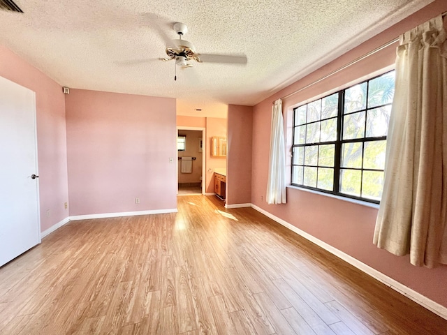 empty room featuring ceiling fan, a textured ceiling, and light hardwood / wood-style flooring