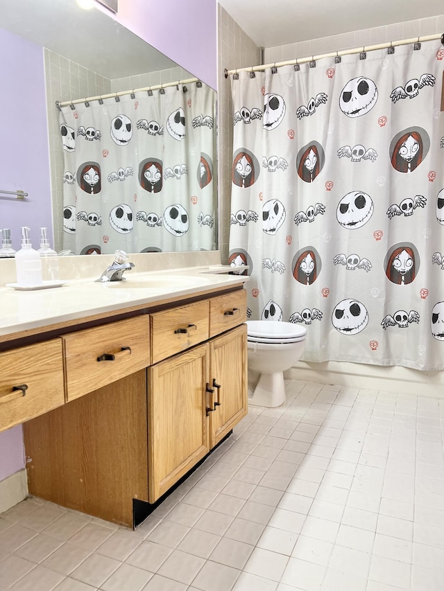 bathroom with toilet, vanity, and tile patterned flooring