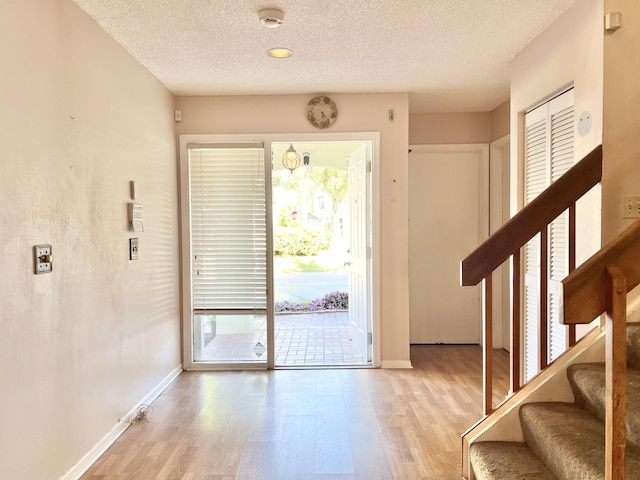 entryway featuring a wealth of natural light, a textured ceiling, and light hardwood / wood-style floors