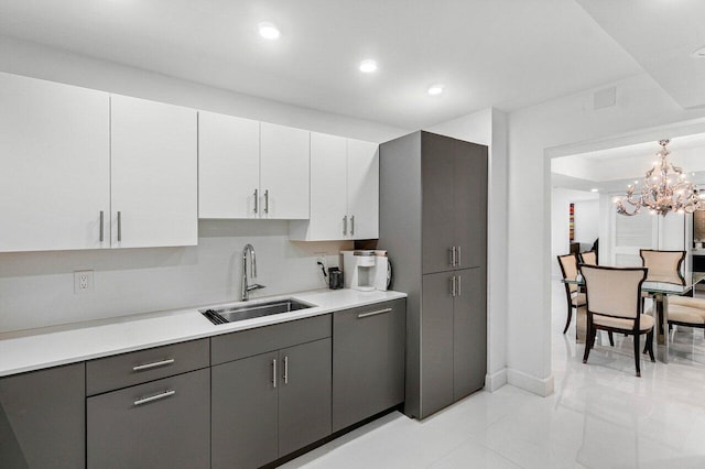 kitchen featuring hanging light fixtures, white cabinetry, gray cabinets, sink, and a notable chandelier