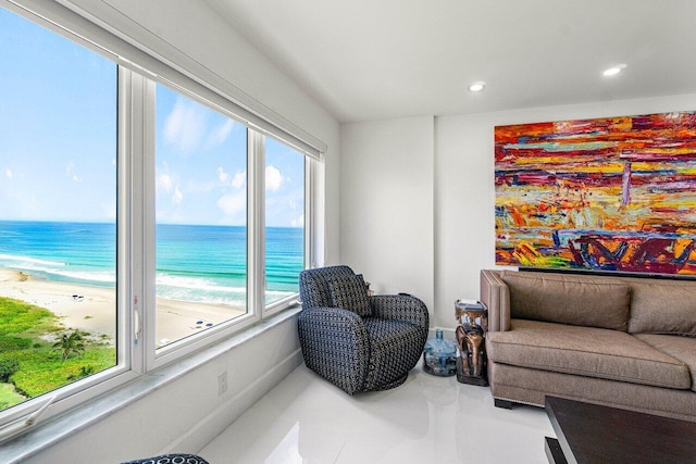 living room with a view of the beach, a wealth of natural light, and a water view