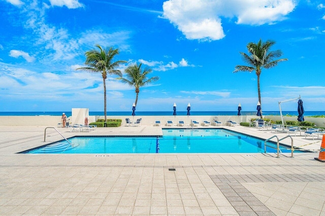 view of pool with a water view and a patio area