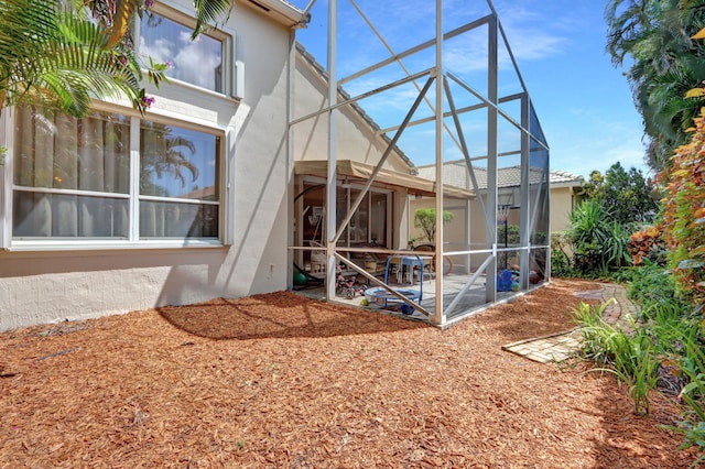 back of property with glass enclosure and a patio area