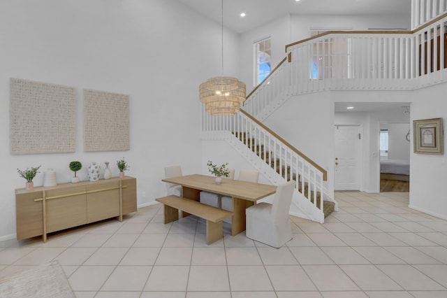 stairs featuring tile patterned flooring, a notable chandelier, and a towering ceiling