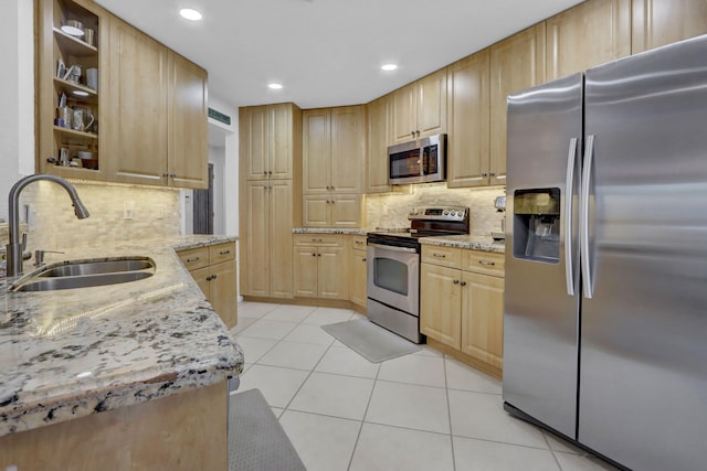 kitchen with light stone counters, stainless steel appliances, sink, and light brown cabinets