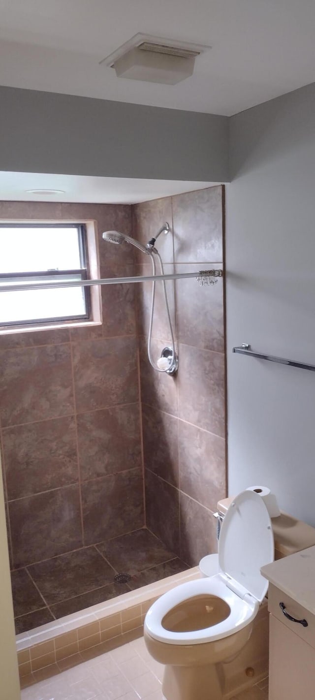 bathroom featuring vanity, toilet, and a tile shower