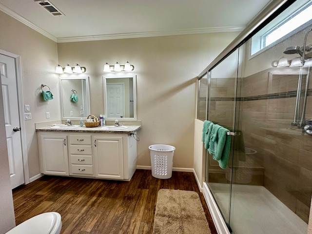 bathroom featuring vanity, wood-type flooring, ornamental molding, toilet, and an enclosed shower