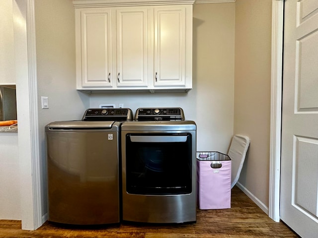 laundry area featuring dark wood-type flooring, independent washer and dryer, and cabinets