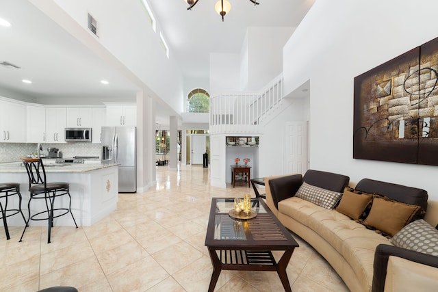 living room with a high ceiling, light tile patterned flooring, and visible vents