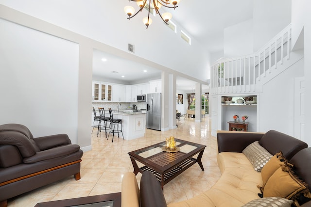 living room with visible vents, baseboards, a chandelier, a towering ceiling, and light tile patterned flooring