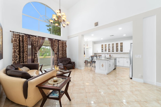 living room featuring a chandelier, visible vents, baseboards, and a towering ceiling