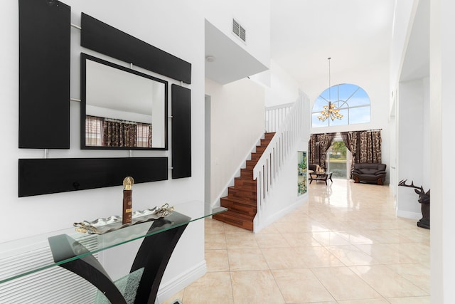 entryway with stairway, baseboards, visible vents, a towering ceiling, and a notable chandelier