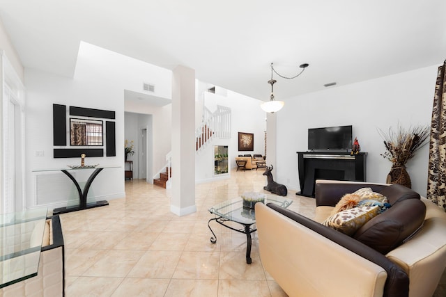 living area featuring stairway, baseboards, visible vents, and a fireplace