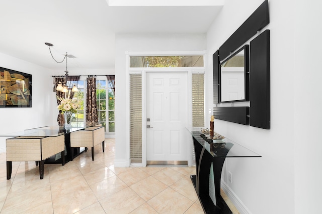 foyer entrance with a chandelier, light tile patterned floors, and baseboards