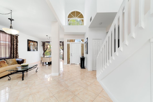 foyer featuring baseboards, plenty of natural light, a towering ceiling, and stairs