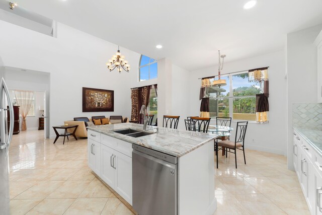 kitchen featuring light stone counters, a chandelier, dishwasher, and a sink