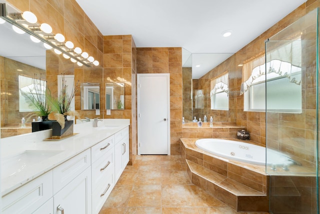 bathroom featuring double vanity, a whirlpool tub, tile walls, and a sink